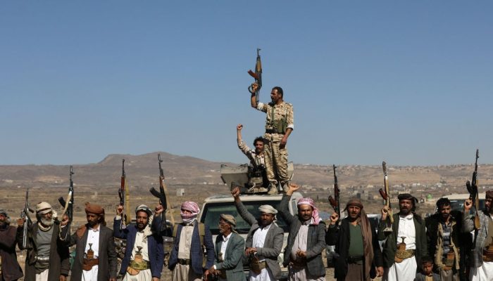 Combatentes houthis e apoiadores seguram suas armas durante protesto contra recentes ataques lide...