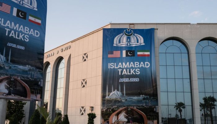 Faixas anunciando conversas entre EUA e Irã no Centro de Convenções Jinnah, onde a imprensa in...