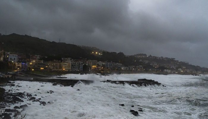 Ondas violentas quebram ao longo da costa entre Aci Castello e os Faraglioni di Aci Trezza, enqua...