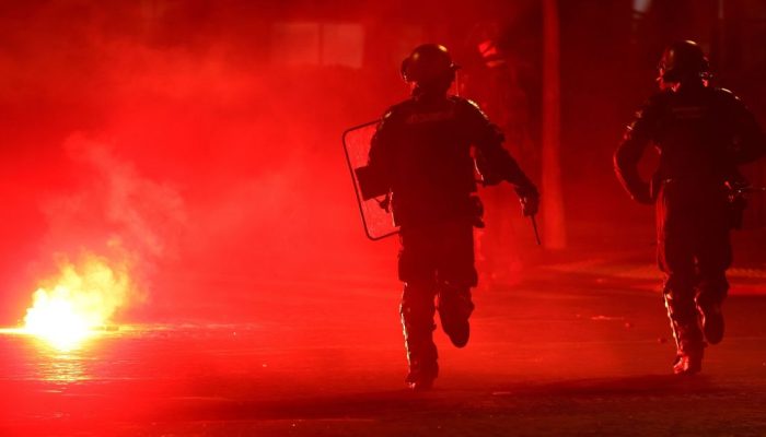 Policiais se protegem de sinalizador em meio a tumulto em Paris durante comemoração do título ...